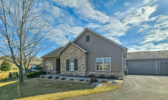 view of front of house with driveway, stone siding, and a front lawn