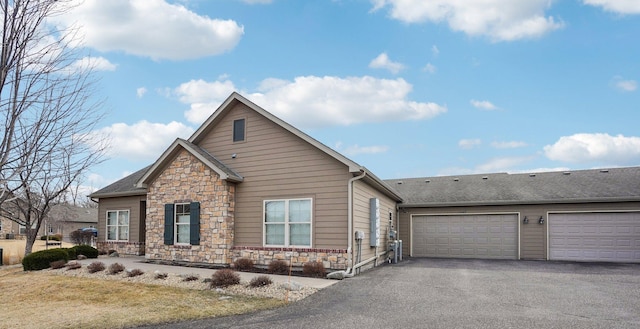 view of front facade featuring a garage, stone siding, and driveway