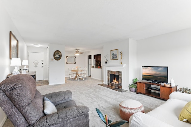 living room with baseboards, a fireplace, a ceiling fan, and carpet