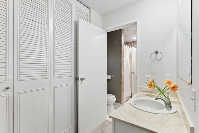 bathroom featuring a closet, toilet, and vanity