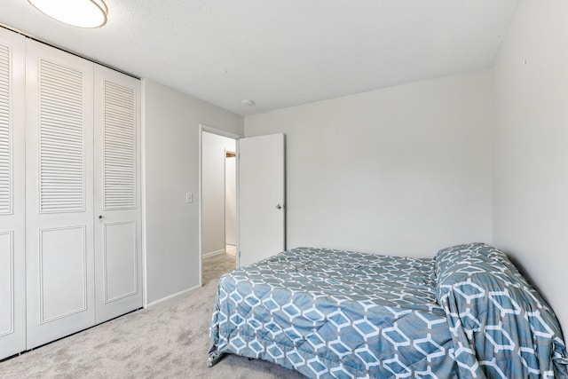 bedroom with a closet, baseboards, carpet, and a textured ceiling