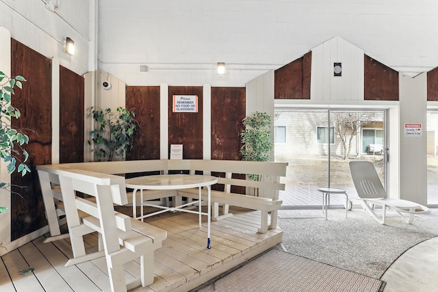 dining area featuring lofted ceiling and wood walls