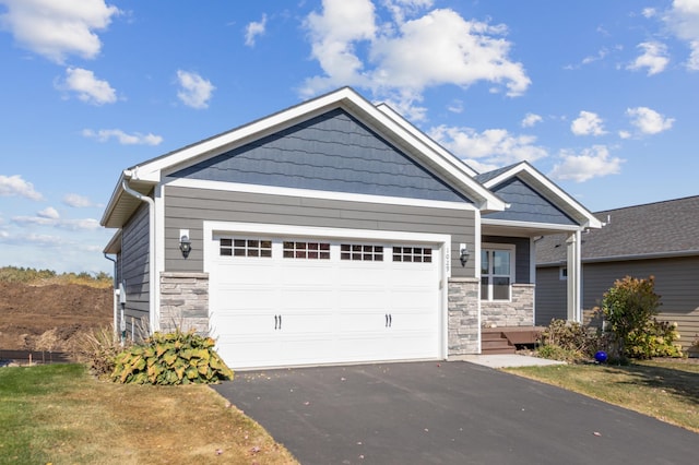 craftsman inspired home with stone siding, driveway, and an attached garage