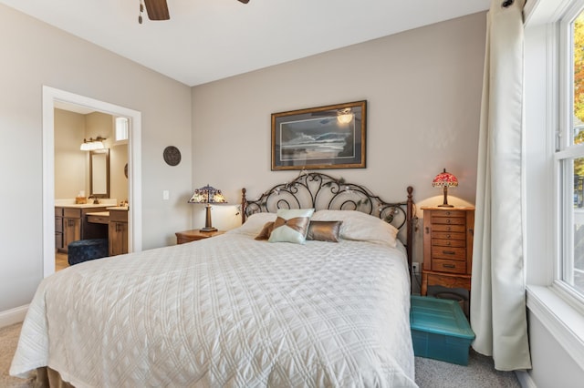 carpeted bedroom with a ceiling fan, baseboards, and ensuite bath