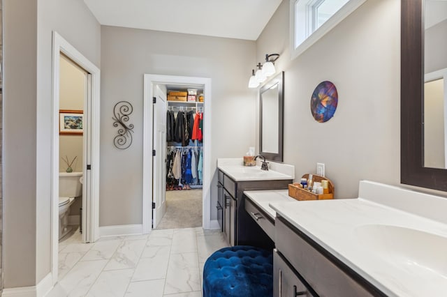 bathroom with marble finish floor, a sink, toilet, and baseboards