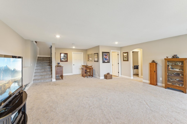 carpeted living room featuring arched walkways, recessed lighting, stairs, and baseboards