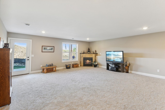 unfurnished living room featuring a warm lit fireplace, carpet floors, recessed lighting, and baseboards