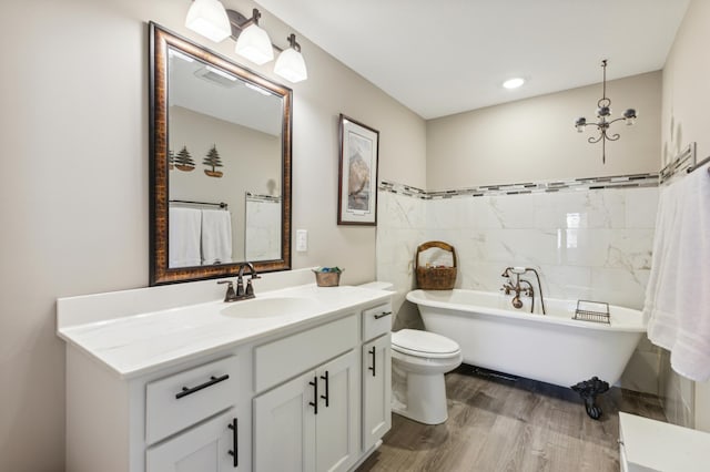 full bath featuring toilet, wood finished floors, vanity, tile walls, and a soaking tub