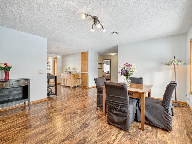 dining area featuring visible vents, baseboards, and wood finished floors