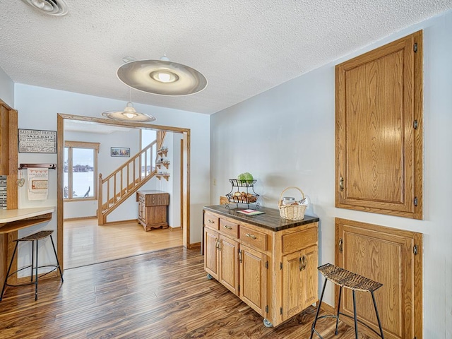 interior space with dark countertops, brown cabinetry, a kitchen breakfast bar, and wood finished floors