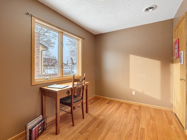 office featuring a textured ceiling, baseboards, visible vents, and light wood-style floors