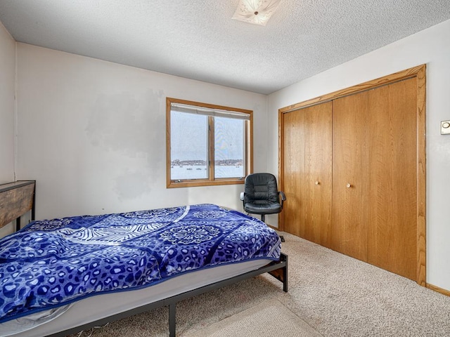 carpeted bedroom featuring a textured ceiling and a closet