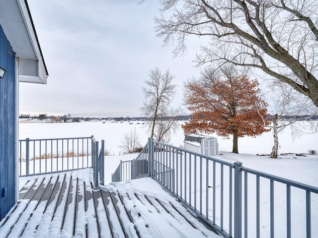 snow covered deck featuring a storage shed and an outdoor structure