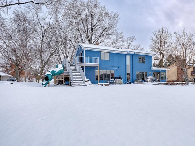 snow covered house featuring a playground