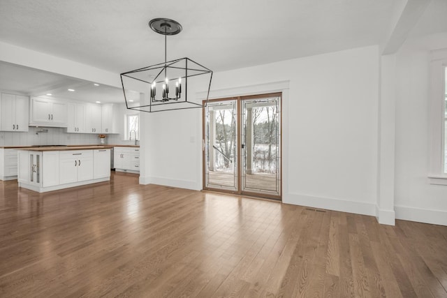 unfurnished dining area with sink, an inviting chandelier, and light hardwood / wood-style flooring