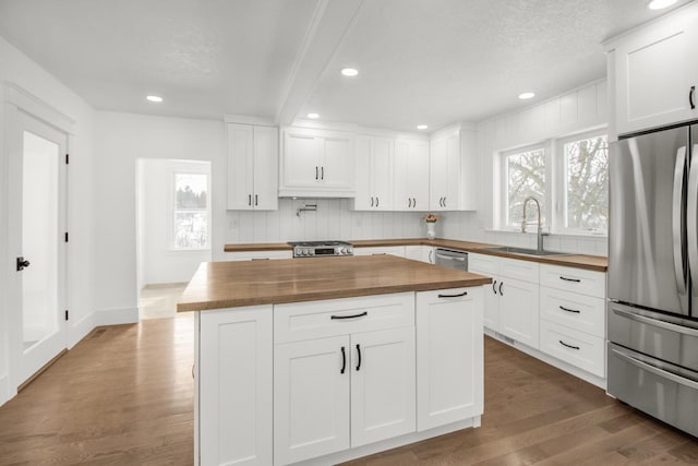 kitchen with hardwood / wood-style floors, butcher block countertops, white cabinetry, sink, and stainless steel appliances