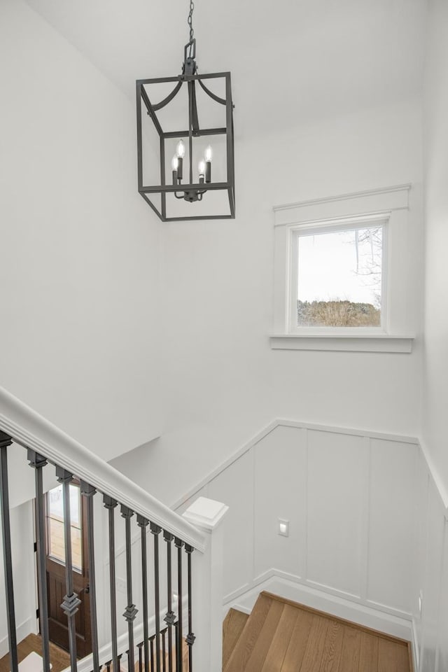 stairway with an inviting chandelier and hardwood / wood-style flooring