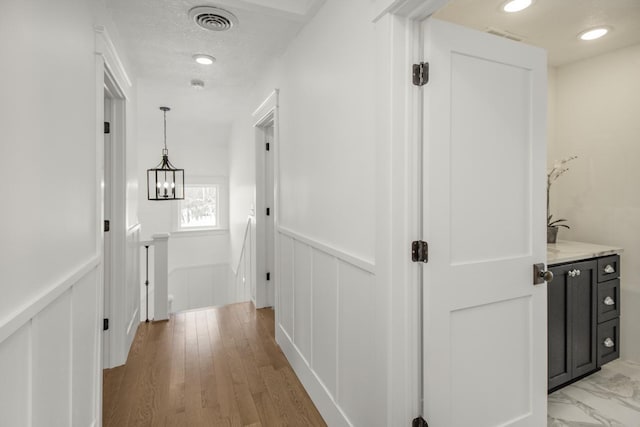 hallway with light hardwood / wood-style floors and a textured ceiling