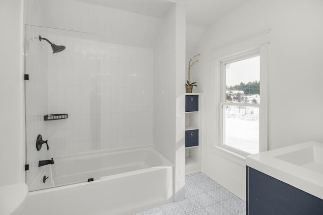 bathroom with tiled shower / bath, vanity, and lofted ceiling