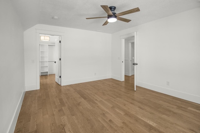 unfurnished room with ceiling fan, a textured ceiling, and light wood-type flooring