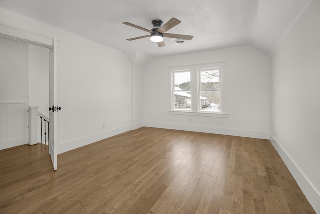 additional living space featuring hardwood / wood-style flooring, vaulted ceiling, a textured ceiling, and ceiling fan