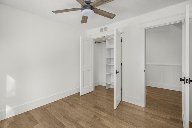 unfurnished bedroom featuring hardwood / wood-style flooring, ceiling fan, a closet, and a textured ceiling