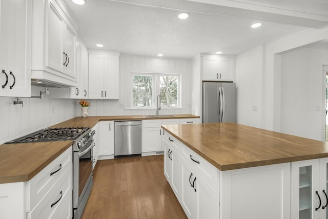 kitchen with a sink, appliances with stainless steel finishes, butcher block counters, and dark wood-type flooring