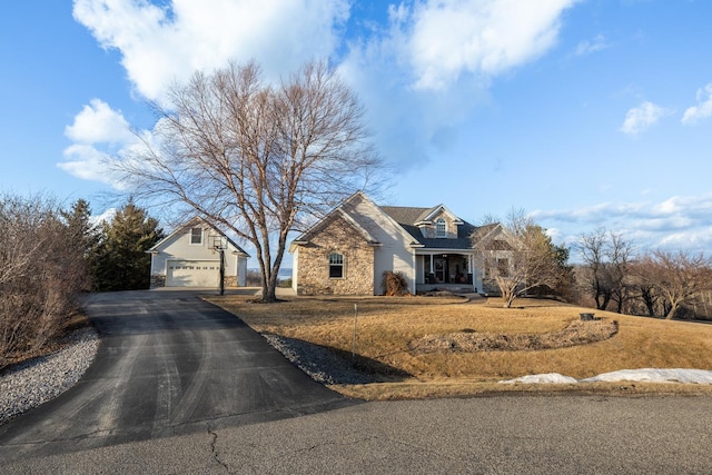 view of front of home featuring covered porch, stone siding, an outdoor structure, and a detached garage