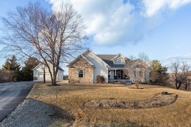 view of front facade with stone siding, a front yard, covered porch, and an outdoor structure