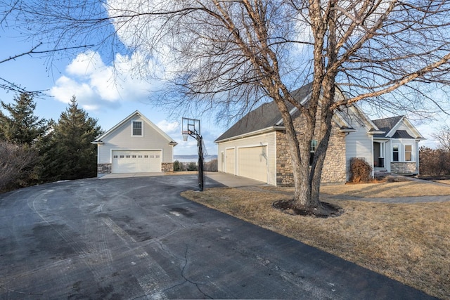 view of side of property with a garage, stone siding, and an outdoor structure