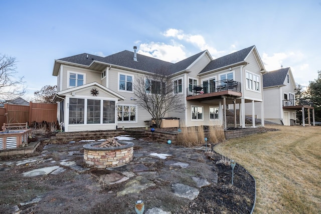 rear view of house featuring a sunroom, fence, and a fire pit