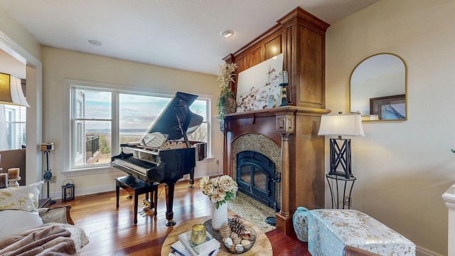 living area with wood-type flooring, a fireplace, and baseboards