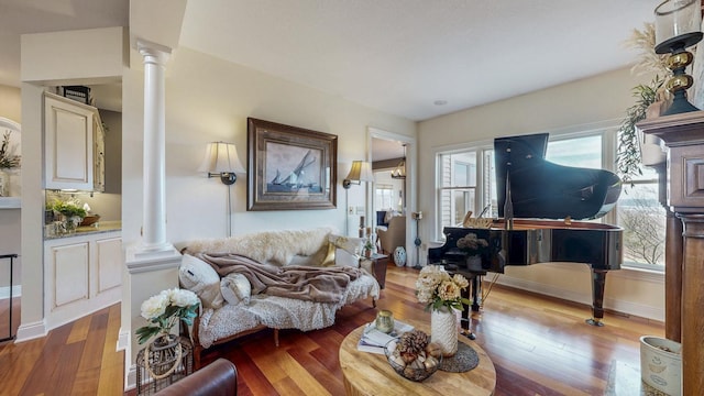 living room with decorative columns, baseboards, and wood-type flooring