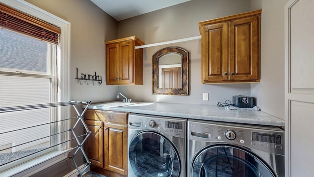 clothes washing area featuring a sink, washing machine and dryer, and cabinet space