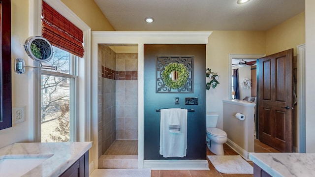 full bath featuring baseboards, toilet, tile patterned flooring, a tile shower, and vanity