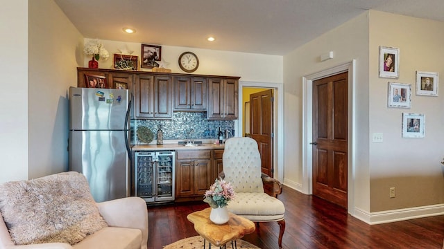 kitchen with decorative backsplash, dark wood finished floors, wine cooler, freestanding refrigerator, and light countertops