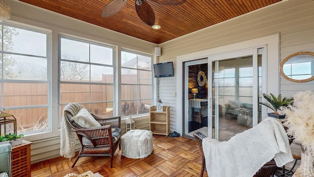 sunroom featuring wooden ceiling and a ceiling fan