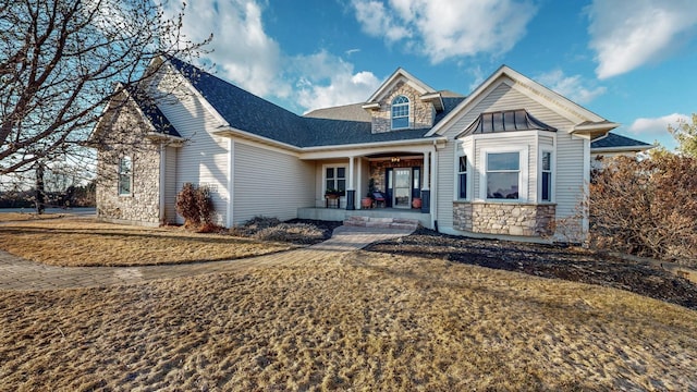 view of front of property with stone siding, a porch, and roof with shingles