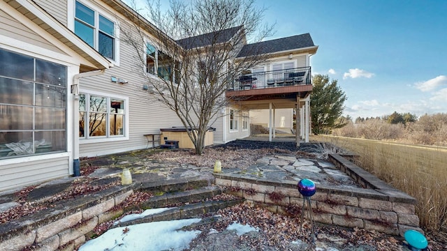 back of property featuring a patio, a wooden deck, and a hot tub