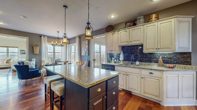 kitchen with tasteful backsplash, an inviting chandelier, a sink, and a kitchen breakfast bar