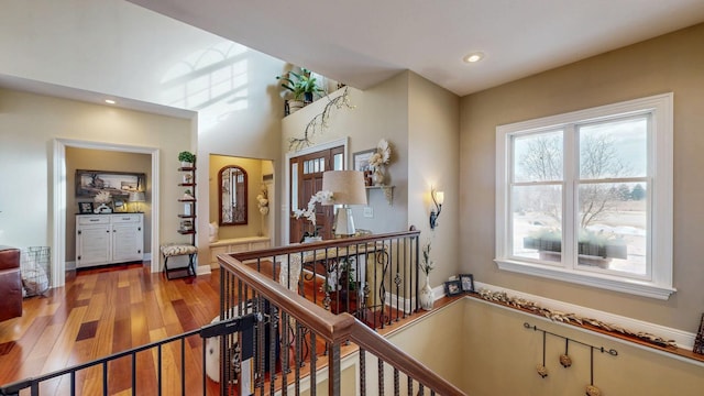 corridor with light wood-style flooring, an upstairs landing, recessed lighting, and baseboards