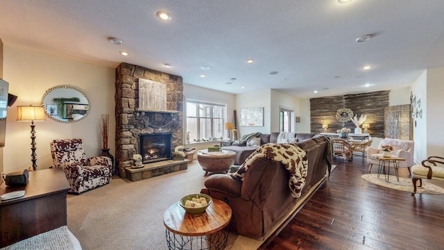 living room with a stone fireplace, recessed lighting, and hardwood / wood-style flooring