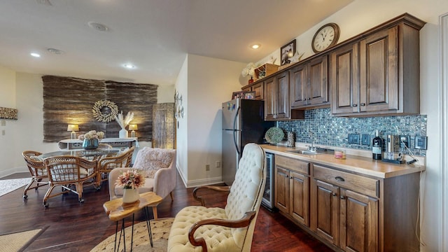 kitchen featuring tasteful backsplash, baseboards, light countertops, freestanding refrigerator, and a sink