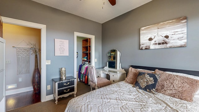 bedroom featuring a closet, baseboards, a ceiling fan, a walk in closet, and carpet flooring
