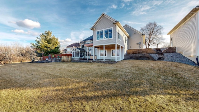 rear view of house with a lawn and stairs