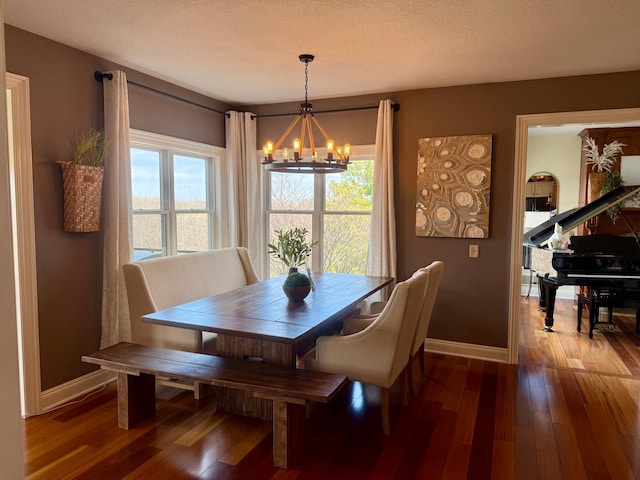 dining room with a notable chandelier, baseboards, and wood finished floors