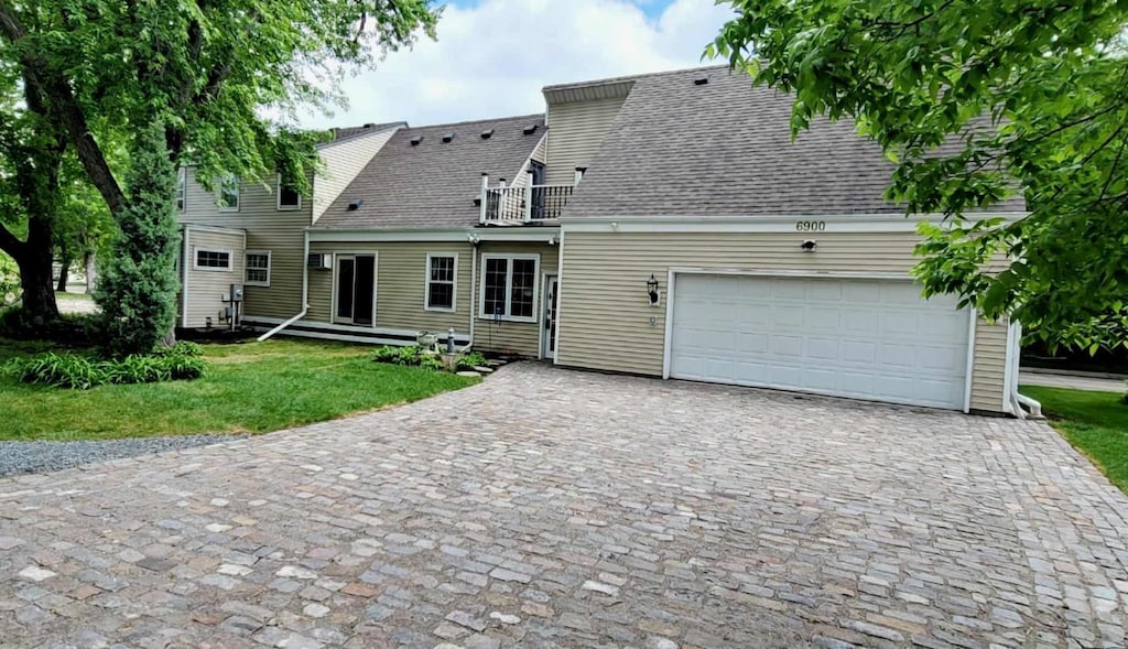 view of front of home with a balcony, a garage, and a front yard