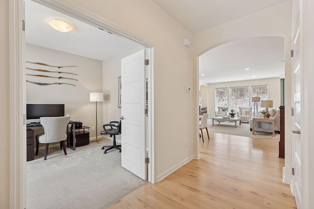 hall with arched walkways, baseboards, carpet, and wood finished floors