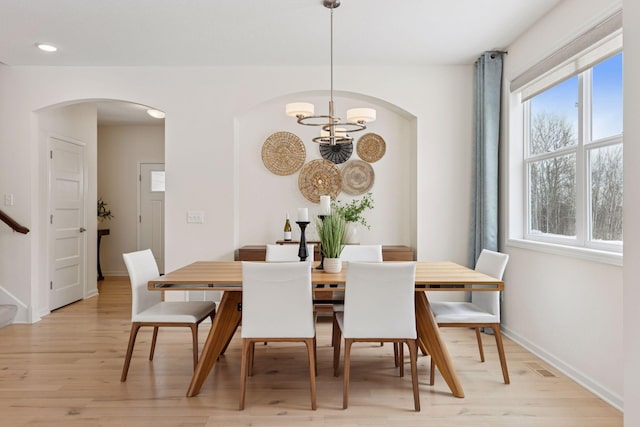 dining area with light wood finished floors, baseboards, arched walkways, a notable chandelier, and recessed lighting