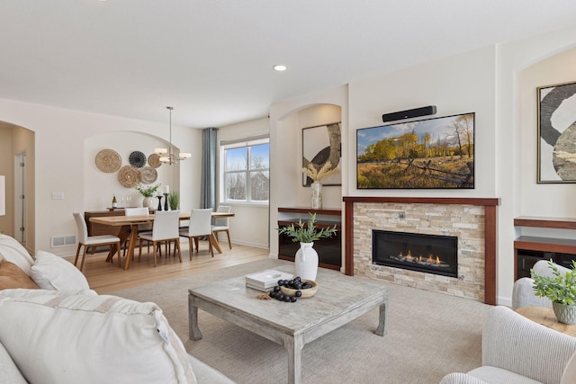 living room with visible vents, a fireplace, baseboards, and wood finished floors